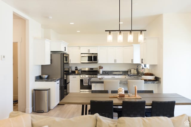 4745 E Silver Moon Dr, Eagle Mountain, UT 84005 - kitchen featuring stainless steel appliances, a sink, dark countertops, light wood-style flooring, and white cabinetry