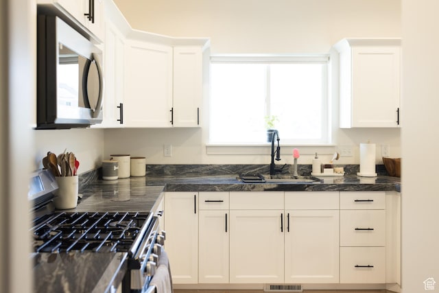 4745 E Silver Moon Dr, Eagle Mountain, UT 84005 - kitchen featuring appliances with stainless steel finishes, white cabinetry, a sink, and dark stone counters