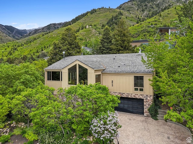 4517 S Abinadi Rd, Millcreek, UT 84124 - view of front of house featuring stone siding, a mountain view, concrete driveway, a garage, and a shingled roof