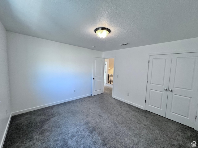 12754 S Quail Lake Dr Unit 126, Riverton, UT 84096 - unfurnished bedroom with dark colored carpet, a textured ceiling, baseboards, and a closet