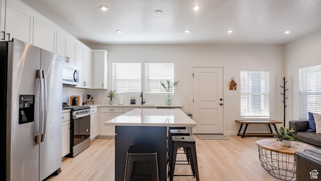 4357 E Longleaf Ln, Eagle Mountain, UT 84005 - kitchen with stainless steel appliances, a breakfast bar, light countertops, light wood finished floors, and recessed lighting