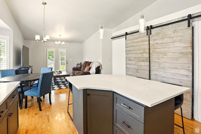 146 S 1125 W, Layton, UT 84041 - kitchen with a barn door, lofted ceiling, a breakfast bar area, gray cabinets, and light wood-type flooring