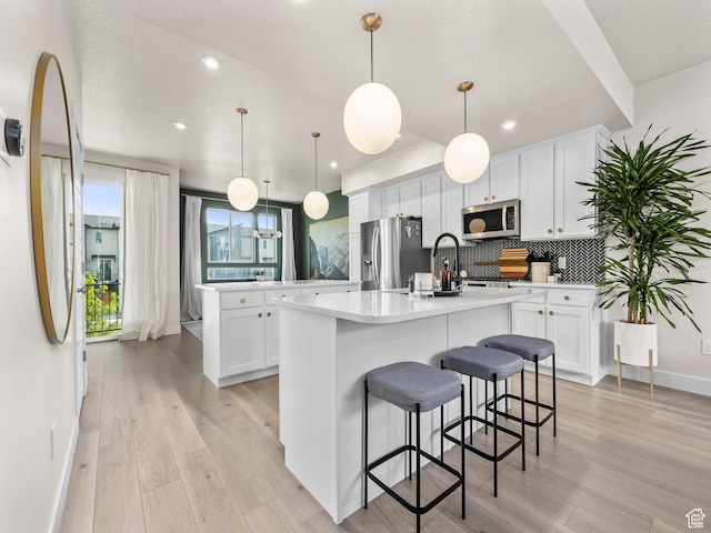 1031 W 360 S, American Fork, UT 84003 - kitchen with appliances with stainless steel finishes, an island with sink, decorative backsplash, white cabinets, and recessed lighting