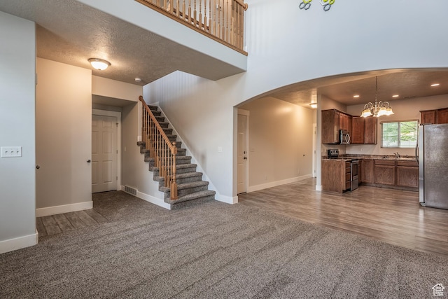 5242 W Cool Water Way S, West Jordan, UT 84081 - unfurnished living room featuring carpet flooring, arched walkways, a chandelier, a sink, and baseboards