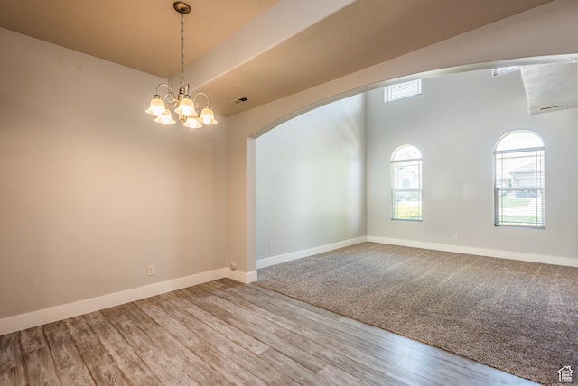 5242 W Cool Water Way S, West Jordan, UT 84081 - empty room featuring arched walkways, wood finished floors, baseboards, and a chandelier