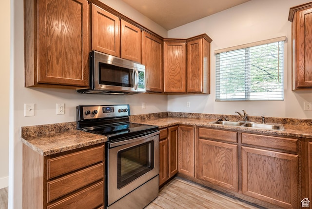 5242 W Cool Water Way S, West Jordan, UT 84081 - kitchen featuring stainless steel appliances, a sink, light wood-style flooring, and dark countertops