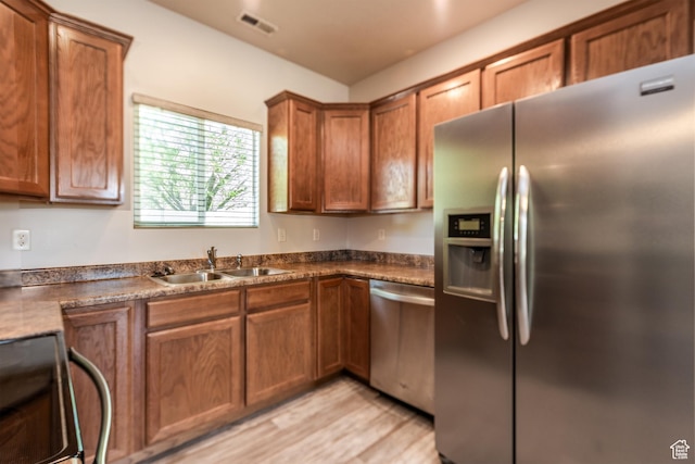5242 W Cool Water Way S, West Jordan, UT 84081 - kitchen with appliances with stainless steel finishes, a sink, brown cabinetry, dark countertops, and light wood-type flooring