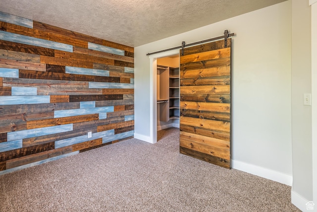 5242 W Cool Water Way S, West Jordan, UT 84081 - unfurnished bedroom featuring wood walls, carpet flooring, baseboards, a walk in closet, and a barn door