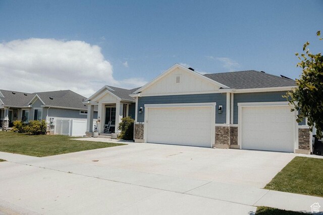 217 S 1230 W Unit 15, Spanish Fork, UT 84660 - view of front of house featuring an attached garage, board and batten siding, a front lawn, concrete driveway, and stone siding