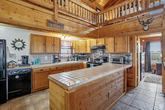 9911 S Antelope Xing, Duchesne, UT 84021 - kitchen with black appliances, tile counters, under cabinet range hood, tasteful backsplash, and stone tile floors