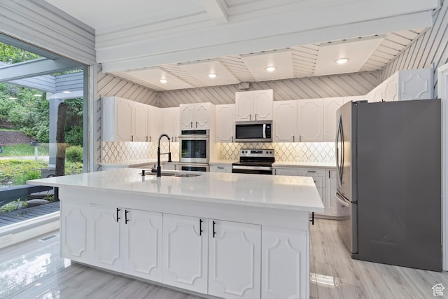 4203 S College Dr E, Ogden, UT 84403 - kitchen featuring appliances with stainless steel finishes, a sink, white cabinets, tasteful backsplash, and a center island with sink