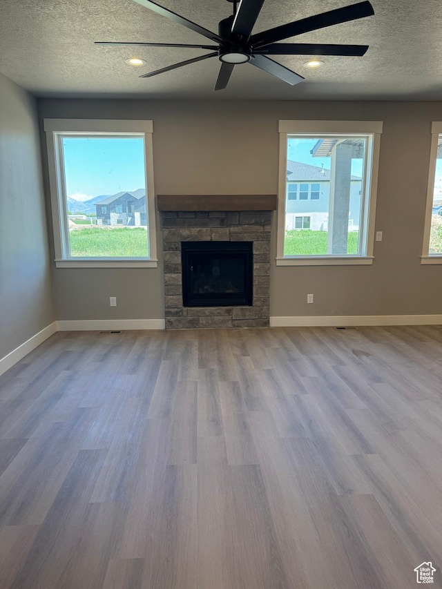 1234 N 4950 W, Plain City, UT 84404 - unfurnished living room featuring wood finished floors, a fireplace, a textured ceiling, a ceiling fan, and baseboards