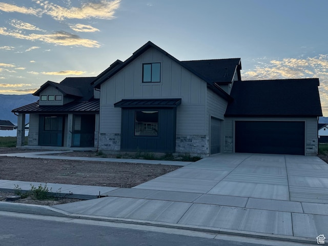 1234 N 4950 W, Plain City, UT 84404 - modern farmhouse featuring stone siding, a standing seam roof, concrete driveway, board and batten siding, and an attached garage