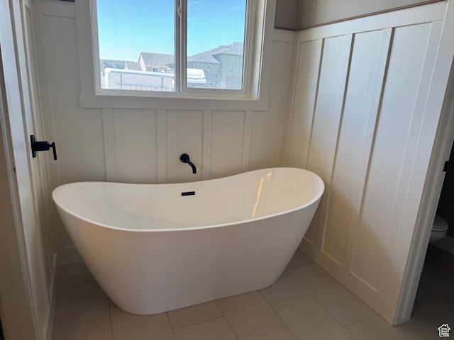 1234 N 4950 W, Plain City, UT 84404 - bathroom featuring a decorative wall, a soaking tub, toilet, and tile patterned floors