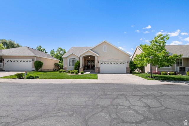 1446 E Anvil Dr, Draper, UT 84020 - view of front facade featuring an attached garage, driveway, stucco siding, and a front lawn