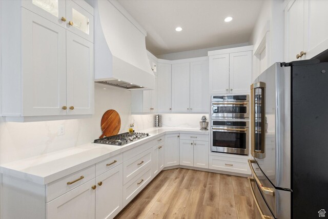 4307 N La Ringhiera Dr, Lehi, UT 84043 - kitchen featuring appliances with stainless steel finishes, premium range hood, white cabinetry, light wood-style flooring, and light countertops