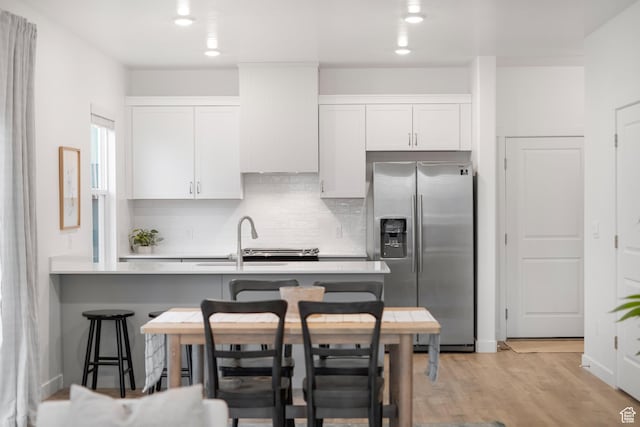 473 N Northshore Dr, Saratoga Springs, UT 84045 - kitchen with stainless steel refrigerator with ice dispenser, decorative backsplash, a breakfast bar area, a sink, and white cabinets
