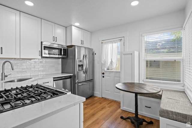 598 Brookside Dr, Springville, UT 84663 - kitchen featuring appliances with stainless steel finishes, a sink, white cabinets, light stone counters, and light wood-type flooring
