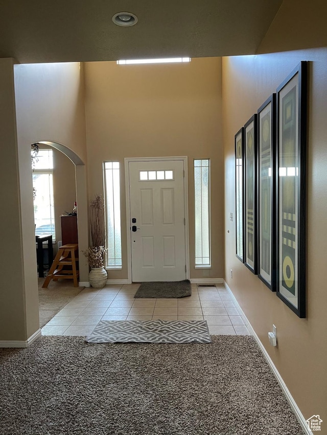 3681 W 775 N, Layton, UT 84041 - entryway with arched walkways, light tile patterned floors, baseboards, a high ceiling, and light colored carpet