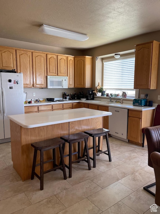 3681 W 775 N, Layton, UT 84041 - kitchen with white appliances, a textured ceiling, a kitchen breakfast bar, light countertops, and a sink
