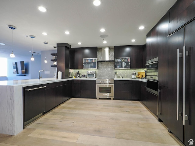 48 W 300 S Unit 2502-N, Salt Lake City, UT 84101 - kitchen with high end appliances, wall chimney range hood, a peninsula, light wood-style flooring, and decorative light fixtures