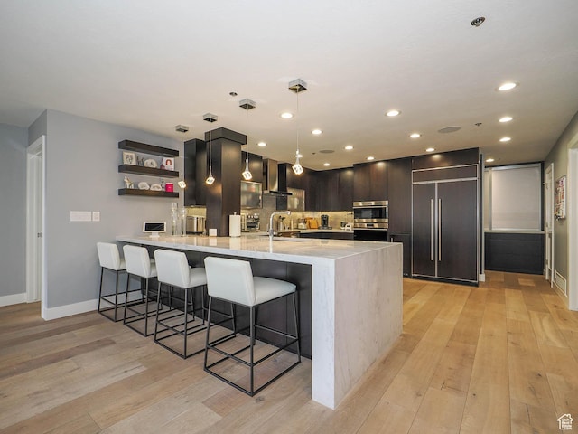 48 W 300 S Unit 2502-N, Salt Lake City, UT 84101 - kitchen featuring wall chimney range hood, paneled built in fridge, a peninsula, light wood-type flooring, and recessed lighting