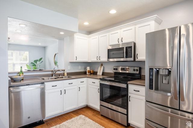 3421 E Dundee Dr, Eagle Mountain, UT 84005 - kitchen featuring stainless steel appliances, a sink, light wood-style floors, white cabinetry, and dark countertops