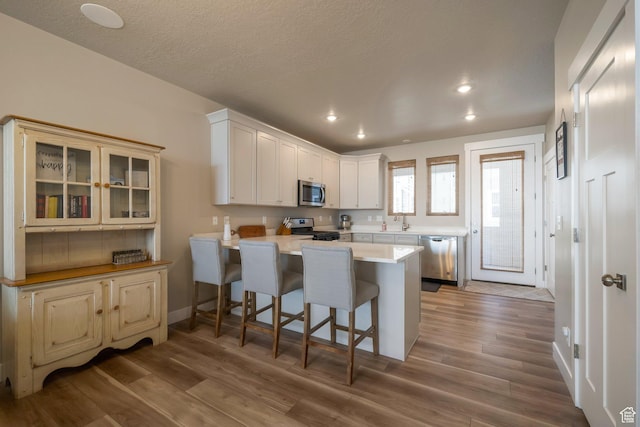 898 S 2560 E, Spanish Fork, UT 84660 - kitchen featuring stainless steel appliances, a peninsula, a kitchen breakfast bar, wood finished floors, and recessed lighting