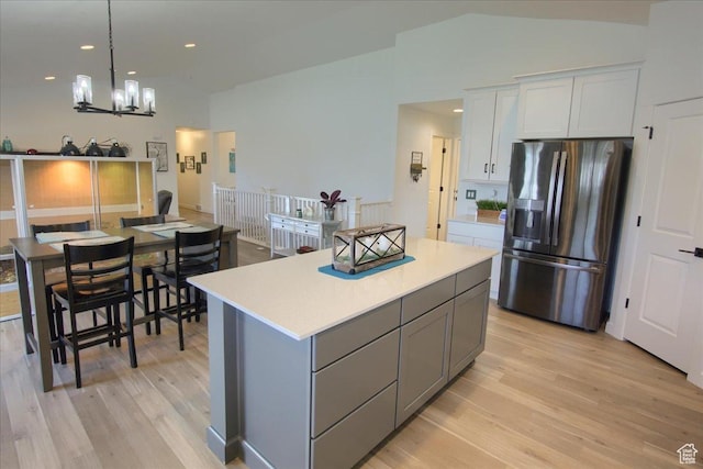 958 W Regatta Ln, Stansbury Park, UT 84074 - kitchen with stainless steel fridge with ice dispenser, light wood-style flooring, a kitchen island, light countertops, and a chandelier