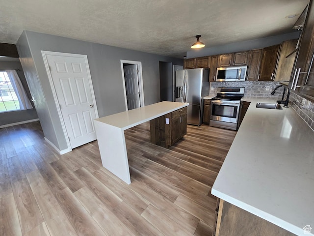 4043 S Lake Vista Dr, Saratoga Springs, UT 84045 - kitchen featuring appliances with stainless steel finishes, a sink, a kitchen island, light countertops, and decorative backsplash