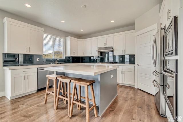 3727 N 900 W, Lehi, UT 84043 - kitchen featuring appliances with stainless steel finishes, under cabinet range hood, a center island, a sink, and a kitchen breakfast bar
