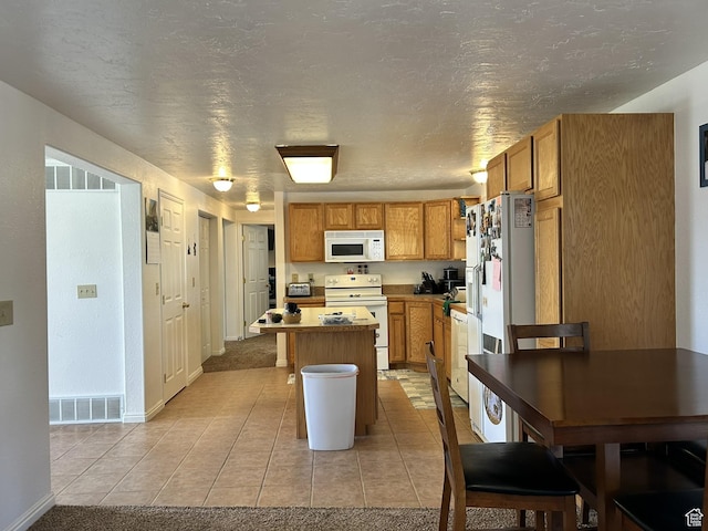 545 E Molen Rd, Ferron, UT 84523 - kitchen featuring white appliances, a kitchen island, light tile patterned floors, baseboards, and brown cabinetry
