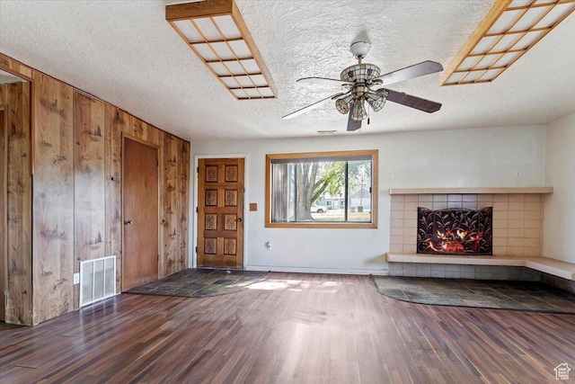 660 S Coleman St, Tooele, UT 84074 - unfurnished living room with wood finished floors, wooden walls, a tile fireplace, ceiling fan, and a textured ceiling