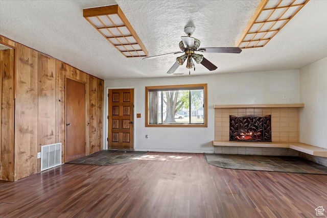 660 S Coleman St, Tooele, UT 84074 - unfurnished living room featuring wood finished floors, wood walls, a ceiling fan, a tile fireplace, and a textured ceiling