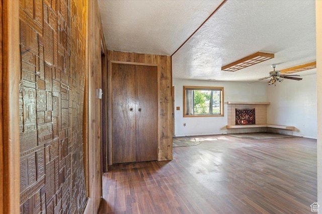 660 S Coleman St, Tooele, UT 84074 - unfurnished living room with a warm lit fireplace, a textured ceiling, a ceiling fan, wooden walls, and wood finished floors