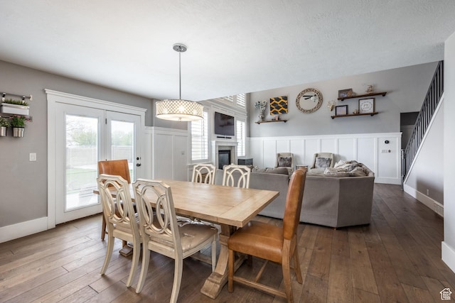 2949 W Hayden Ridge Way, Riverton, UT 84065 - dining space with dark wood-type flooring, a glass covered fireplace, a wainscoted wall, a decorative wall, and baseboards