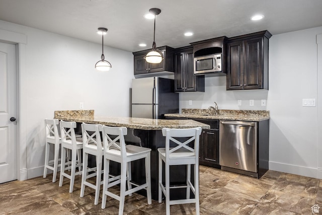 2949 W Hayden Ridge Way, Riverton, UT 84065 - kitchen featuring stainless steel appliances, baseboards, a breakfast bar, light stone counters, and hanging light fixtures