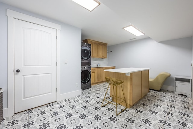 2949 W Hayden Ridge Way, Riverton, UT 84065 - kitchen with stacked washer / drying machine, light countertops, a kitchen island, a breakfast bar area, and baseboards