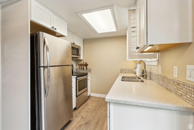 518 E 3955 S, Millcreek, UT 84107 - kitchen featuring stainless steel appliances, a sink, white cabinets, light wood finished floors, and decorative backsplash