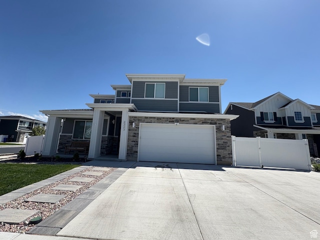 2323 W Thomas Ct, Syracuse, UT 84075 - view of front facade featuring concrete driveway, an attached garage, stone siding, and a gate