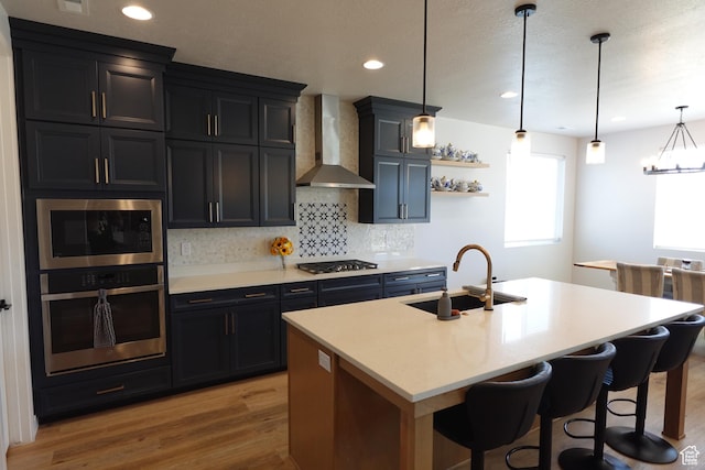2323 W Thomas Ct, Syracuse, UT 84075 - kitchen featuring appliances with stainless steel finishes, a sink, wall chimney range hood, tasteful backsplash, and light wood finished floors