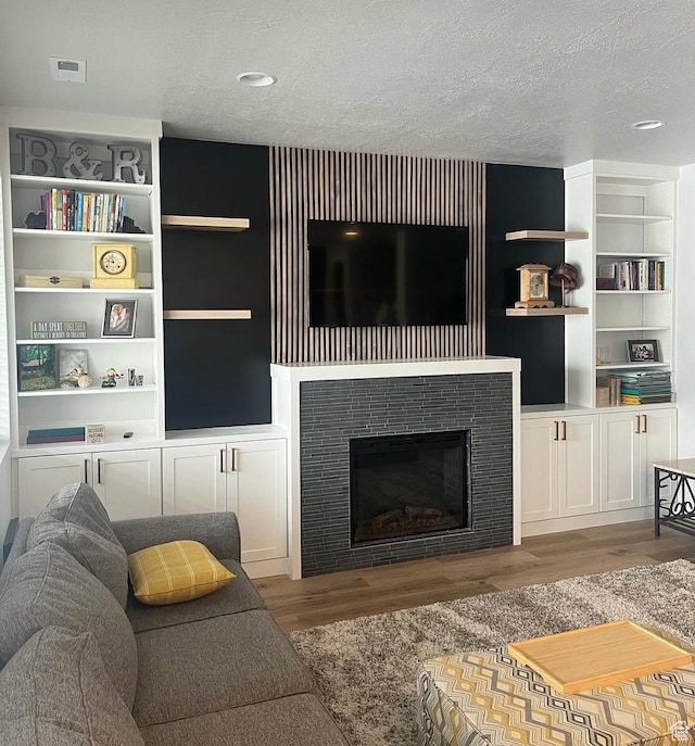2323 W Thomas Ct, Syracuse, UT 84075 - living room with a textured ceiling, wood finished floors, a tile fireplace, and built in shelves