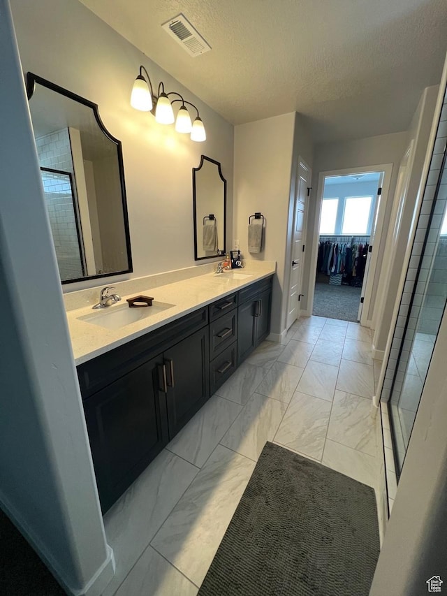 2323 W Thomas Ct, Syracuse, UT 84075 - full bathroom with marble look tile flooring, double vanity, a textured ceiling, a tile shower, and a spacious closet