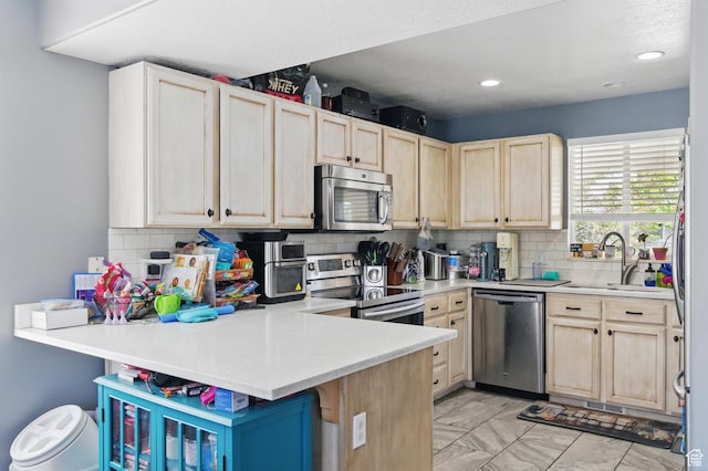 122 W Stern Ct Unit 25, Stansbury Park, UT 84074 - kitchen with stainless steel appliances, a sink, light brown cabinets, backsplash, and a peninsula