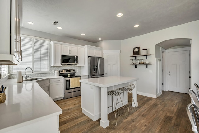 10966 S Coastal Dune Dr, South Jordan, UT 84009 - kitchen featuring appliances with stainless steel finishes, a sink, tasteful backsplash, dark wood-style flooring, and arched walkways