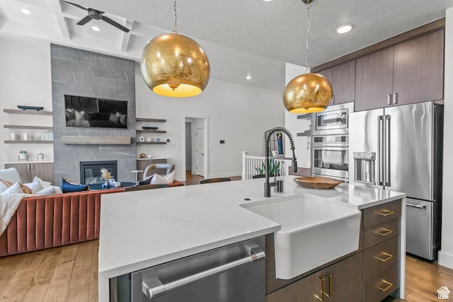 2041 W Pinnacle Ave, Mapleton, UT 84664 - kitchen with appliances with stainless steel finishes, a sink, a tile fireplace, light wood-type flooring, and dark brown cabinets