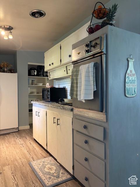 495 E 34 S Unit 10, Orem, UT 84097 - kitchen featuring refrigerator, black microwave, light wood-type flooring, and white cabinets