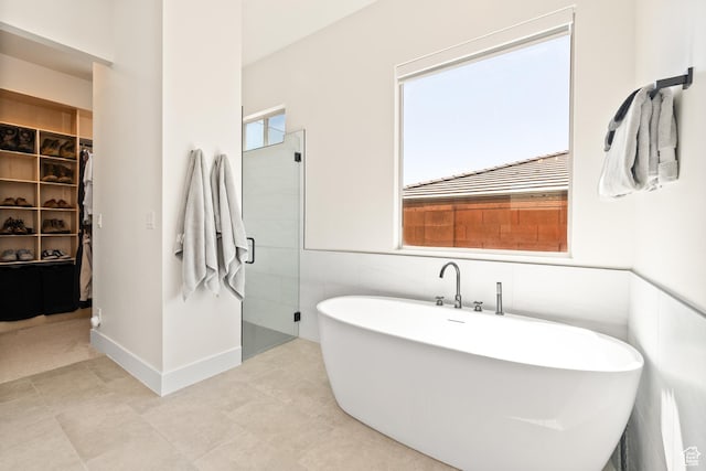423 W Fitness Way, Ivins, UT 84738 - bathroom with a walk in closet, a freestanding bath, a shower stall, tile walls, and tile patterned floors