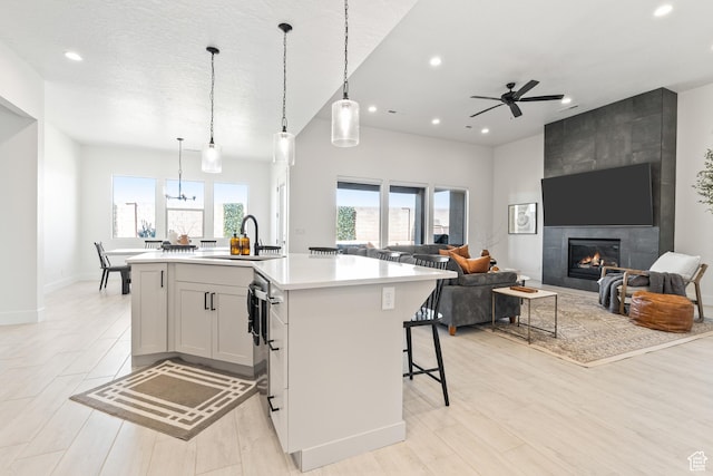 423 W Fitness Way, Ivins, UT 84738 - kitchen featuring recessed lighting, light countertops, a center island with sink, a tile fireplace, and open floor plan