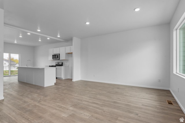 1885 E Thunder Ln Unit 495, Eagle Mountain, UT 84005 - unfurnished living room with light wood-type flooring, recessed lighting, a sink, and baseboards